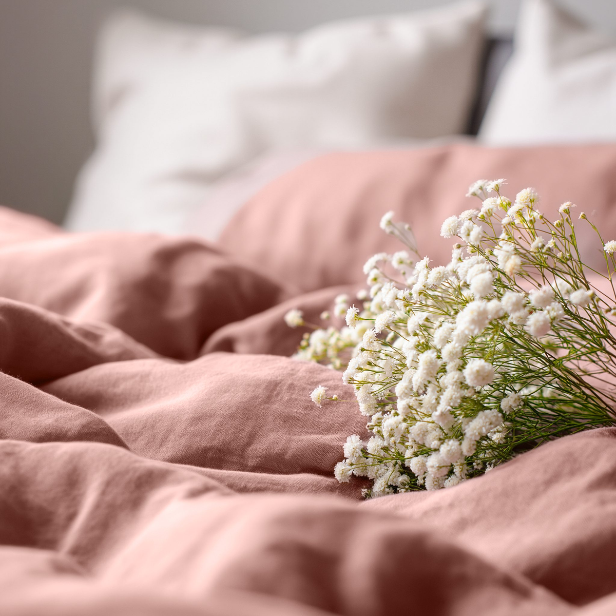 Close-up of Cuddledown linen bedding in Canyon Pink with a bunch of white gypsophila