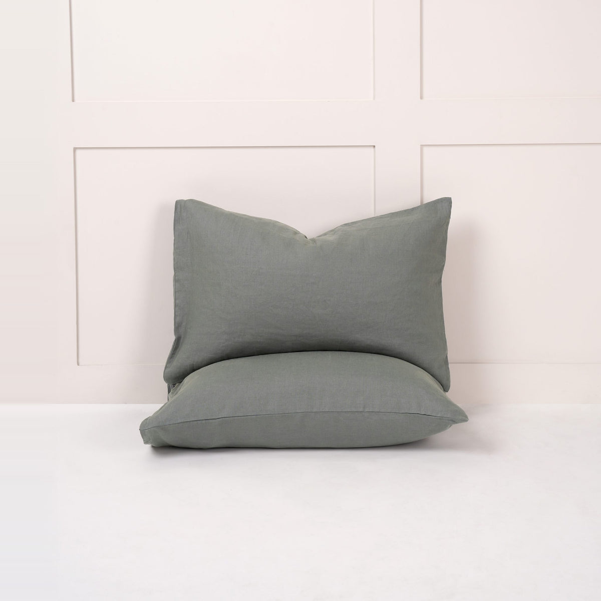Cuddledown linen pillowcases in Sea, pair of pillows propped against a white panelled wall
